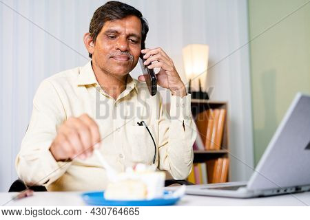 Happt Smiling Businessman Eating Cake While Talking On Moble Phone At Office - Concept Of Unhealthy 