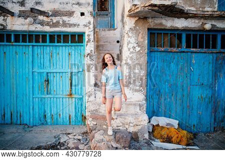 Adorable teenage girl enjoying visit to colorful fishing village of Klima on the island of Milos in Greece