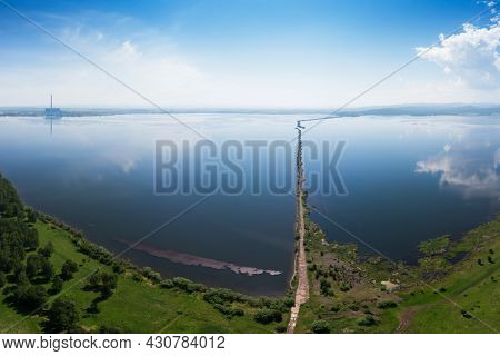Beryozovskoye reservoir - cooling reservoir of Beryozovskaya GRES. Aerial drone view of lake landscape with road in sunny summer. Berezovskaya GRES is a thermal power plant in the town of Sharypovo