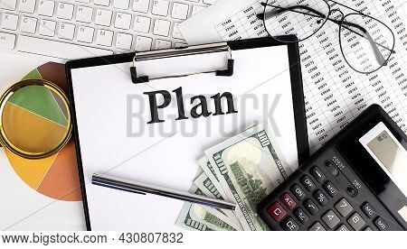 Text Plan On Office Desk Table With Keyboard,dollars,calculator ,supplies,analysis Chart On The Whit