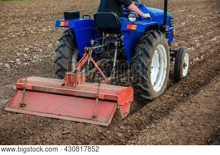 The Tractor Is Cultivating The Soil In The Farm Field. Freeing Milling Earth Ground From Old Crops. 