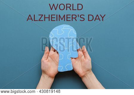 World Alzheimer's Day. Female's Hands Holding A Paper Human Head With Puzzle Ornament. Blurbackgroun