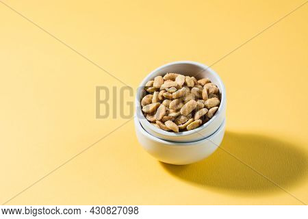 Salted Peanuts In A White Bowl On A Delt Background In Hard Light. Healthy Modern Vegetarian Food.