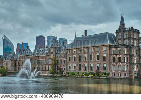 View of the Binnenhof House of Parliament and the Hofvijver lake with downtown skyscrapers in background. The Hague, Netherlands