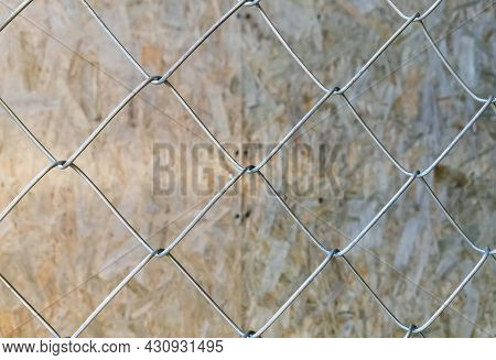 Metal Mesh With Large Square Cells Close-up On The Background Of A Wooden Pavement