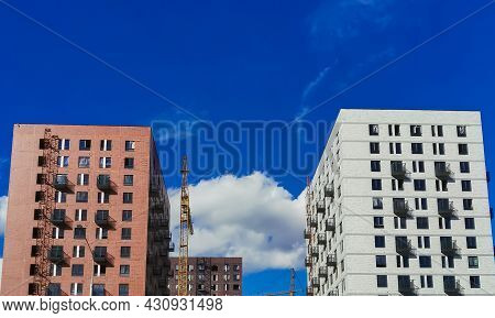 Two Yellow And Red Brick High-rise Buildings Under Construction Against A Bright Blue Sky.