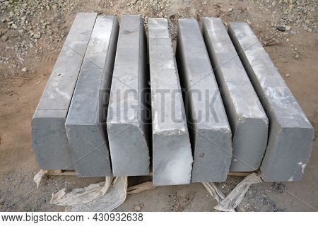 Stack Of Gray Curbstone On Pallet Standing On Pavement. The Pallet With A Stack Of Concrete Curbston
