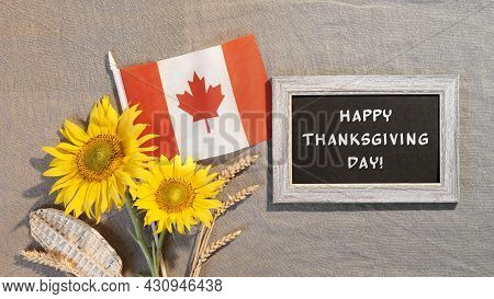 Happy Thanksgiving Text On Blackboard. Canada Flag With Sunflowers And Autumn Decorations. Flat Lay,
