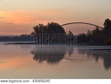 Bank Of The Ob At Dawn. Golden Cream Dawn, Haze Over The Calm Water Of The River, The Reflection Of 
