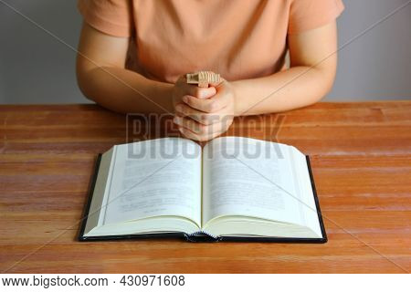 Asian Christain Woman Praying While Holding Wood Cross In Front Of The Bible