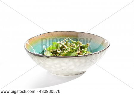 Chinese smashed cucumber with greens and sesame oil. Healthy vegetarian green salad with cracked cucumber and fresh green leaf. Healthy salad recipes concept. Salad bowl isolated on white background