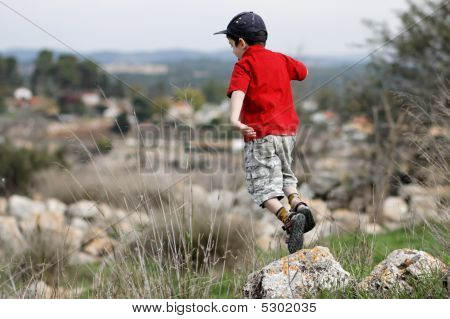 Little Boy in red Shirt springt aus dem Stein im freien