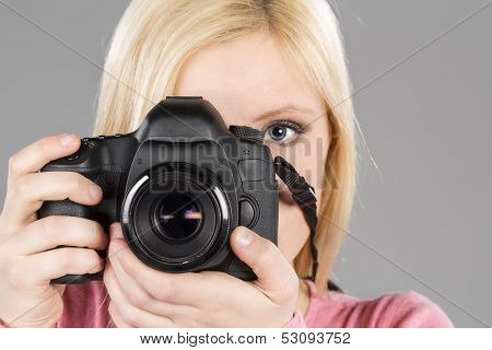 Blonde model holding a camera in a studio environment