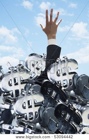 Businessman buried under a large group of dollar signs
