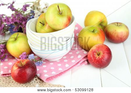 Juicy apples on plate on white wooden table