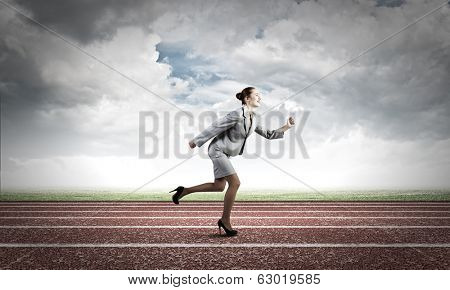 Young businesswoman in suit running on track