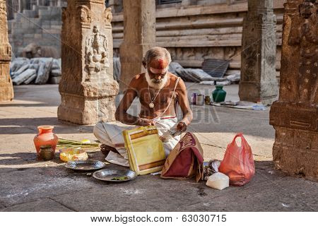 MADURAI, INDIA - FEBRUARY 16, 2013: Indian brahmin (traditional Hindu society) priest with donation in famous Meenakshi Amman Temple - historic Hindu temple located in temple city Madurai