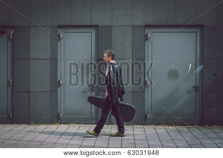 Man In Short Sleeve Shirt Walking With Guitar Case