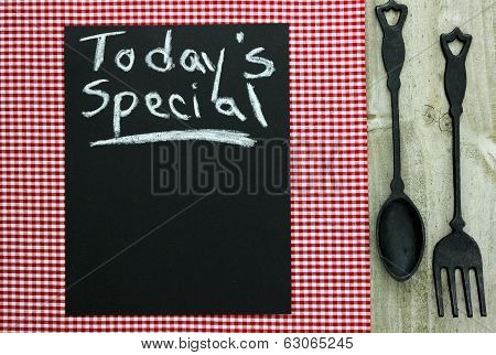 Today's Special on chalkboard with cast iron spoon and fork and red checkered tablecloth