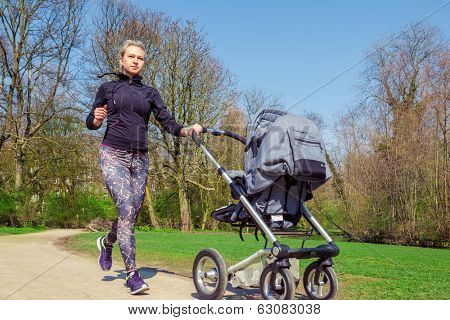 Young mother jogging with a baby buggy