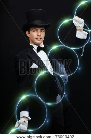 magic, performance, circus, show concept - magician in top hat showing trick with linking rings