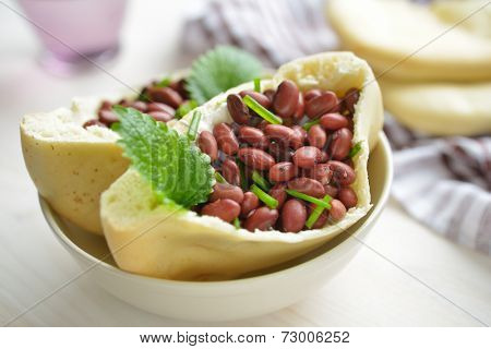 Pita bread with red beans, tzatziki, chives, and mint leaves