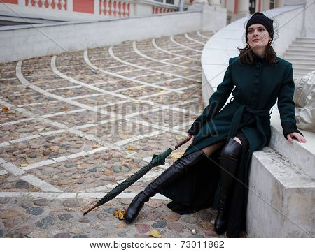 Woman in a green coat posing on stairs