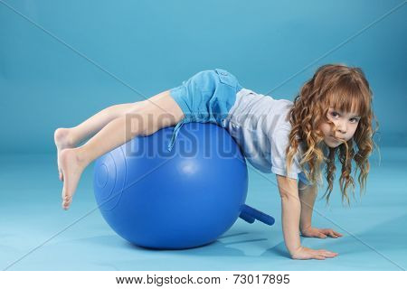5 years old child playing with fitball l on blue studio background