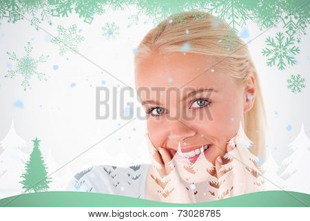 Cute blonde woman smiling at the camera against snowflakes and fir tree in green