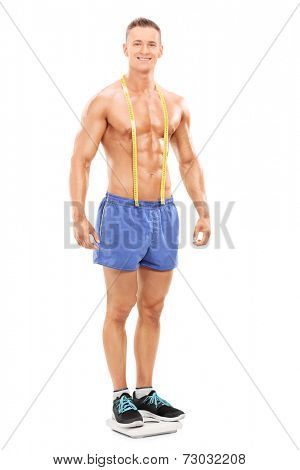 Full length portrait of a handsome man standing on a weight scale isolated on white background