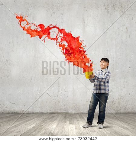 Young boy splashing colorful paint from bucket