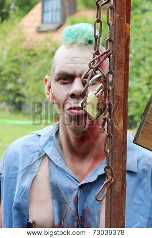 MUSKOGEE, OK - Sept. 13: A bloody zombie holds a metal fence, ready to chase his victims during the Castle Zombie Run at the Castle of Muskogee in Muskogee, OK on September 13, 2014. 