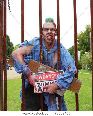 MUSKOGEE, OK - Sept. 13: A bloody zombie holds a metal fence, ready to chase his victims during the Castle Zombie Run at the Castle of Muskogee in Muskogee, OK on September 13, 2014. 