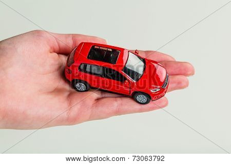 a hand holding the model of a car. symbol photo for car purchase