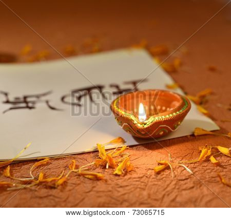Indian traditional lamp placed on a book with Sanskrit calligraphy