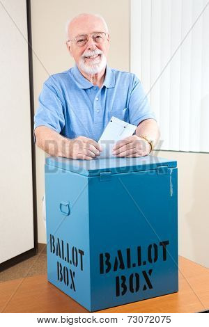 Senior man dropping his ballot in the box at the election polling station.  