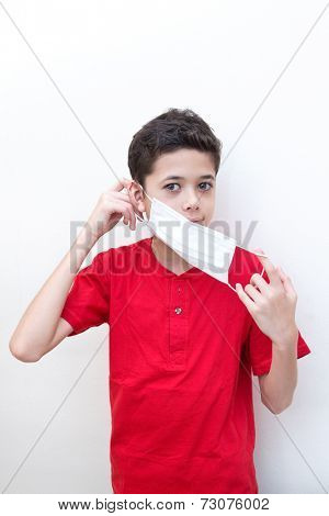 A sick young boy putting on a face mask to stop spread of germs.