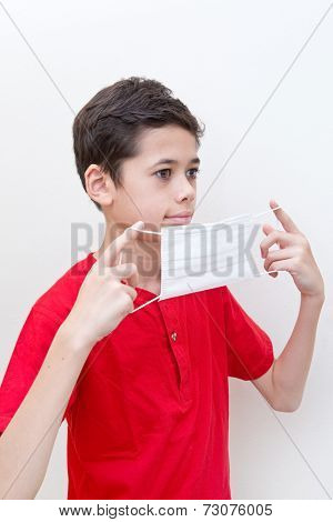  A young boy putting on a face mask to stop spread of germs.