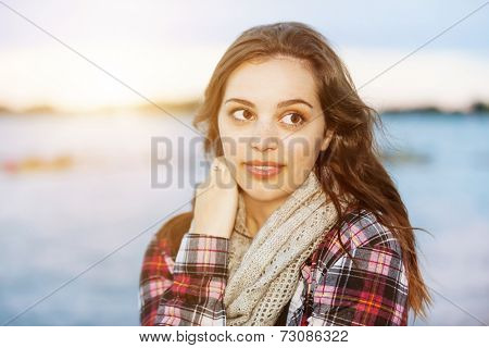 Candid portrait of young brunette woman at sunset looking away with copy space