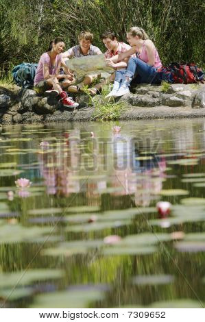 Fire teenagere (16-217 år) sidder ved søen læsning selektiv fokus