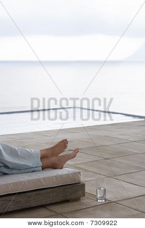 Mujer tendida en la cama del sol por la sección baja de infinity pool