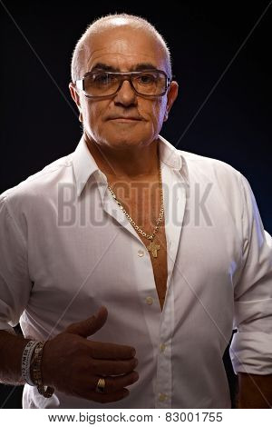 Portrait of old playboy in white shirt and lots of gold jewels.