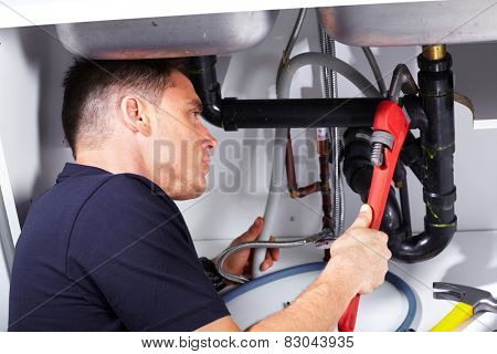 Plumber man with tools in the kitchen. Plumbing and renovation.