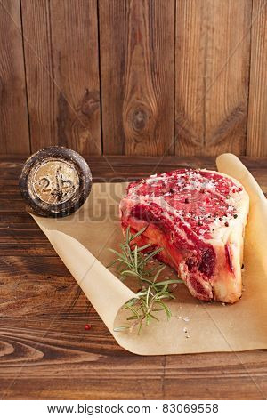 raw beef Rib bone  steak  on paper  and table with 2lb iron weight