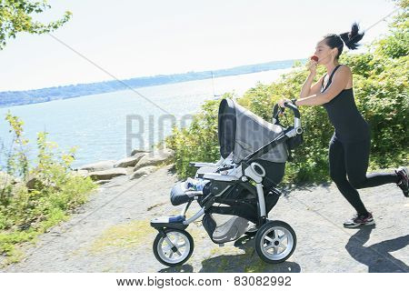 A Young mother jogging with a baby buggy