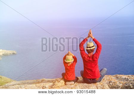 father and son doing yoga in mountains at the sea
