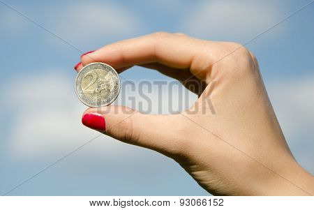 Coin euro in the hands against the sky