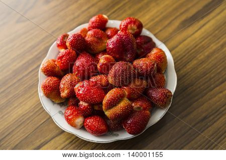 Bowl of strawberries top view on wooden table