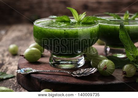 Healthy green fresh fruit and vegetable juice smoothie breackfast with chia seeds garnish and green gooseberry.