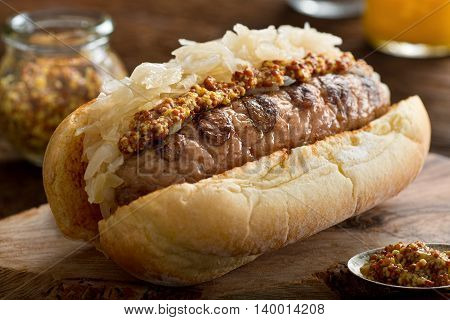 A delicious grilled sausage with sauerkraut and coarse mustard on a toasted hot dog bun.